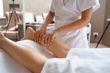 Professional massage therapist massages the soles, legs of adult woman lying on massage table, close-up. Lady gets relaxing massage. Concept of body care.