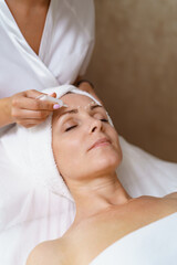 Obraz na płótnie Canvas Face and Eye cream treatment or therapy. Dermatologist applying lotion on female skin
