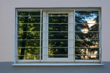 Dirty plastic window on the wall of a building with a metal grill