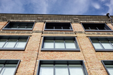 Fototapeta premium Brick building with windows and downspout against blue sky