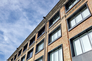 Brick building with windows and downspout against blue sky