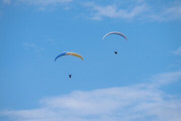 Two paraglider in the blue sky flying together.