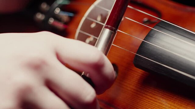 Violinist puts a bow on the strings of the violin and prepares to play, close-up. Concept of violin playing.