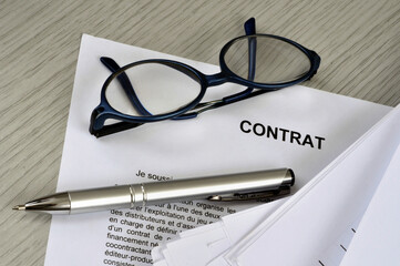 Lunettes et stylo posés sur un contrat