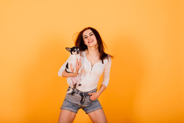 Young woman cuddling chihuahua puppy in studio