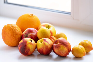 oranges, nectarines, apples and plums on a white windowsill