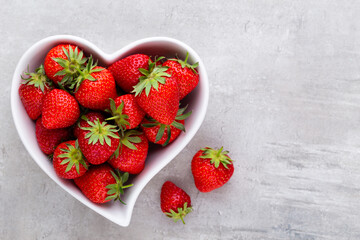 Strawberry heart. Fresh strawberries in plate on white wooden table. Top view, copy space.
