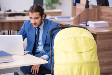 Young male employee looking after new born at workplace