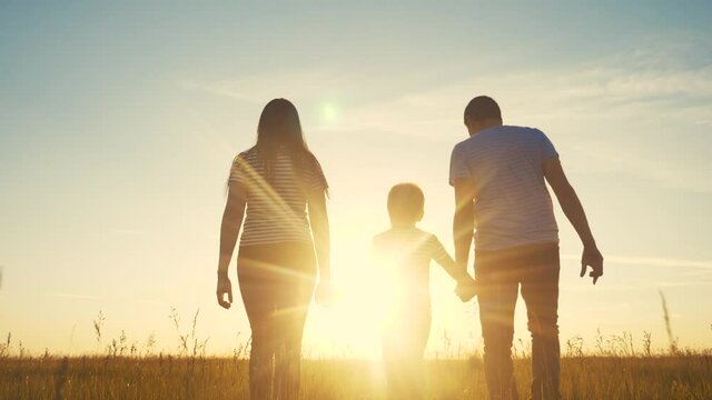 happy family and kid together fun walk at sunset in the park in nature. mom dad and boy son walk outdoor in the park sunset silhouette lifestyle. parents and child together are walking. people in the