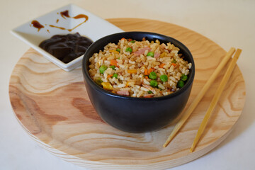 Delcious Special Fried rice in a bowl, soy sauce and Asian Chopsticks in round wooden plate. Top View