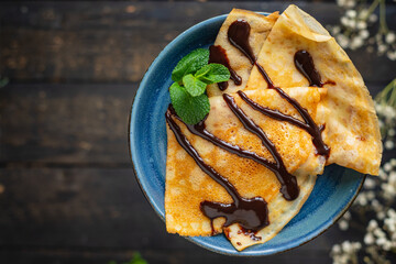thin pancakes pour chocolate crepes syrup white plate flat cake snack meal top view copy space rustic food background 
