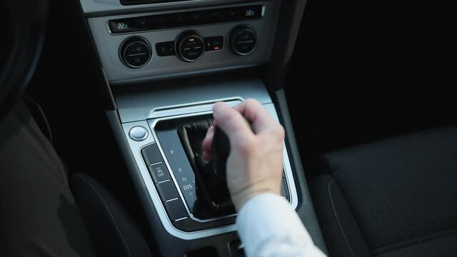 Driver's adm includes mode Drive on the gear lever automatic transmission of the luxury car interior parts. Business man in suit hand control the stick shift transmission.