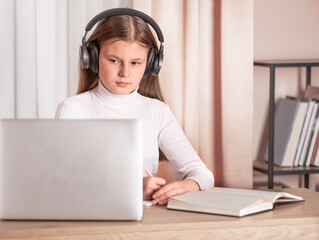 girl wearing headphones using laptop to watch online seminar. E-learning concept. Distance education.