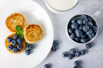 Cottage cheese pancakes, syrniki with blueberry in a white plate.