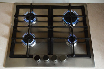 Kitchen gas stove with four burners burning blue flame