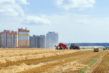 A round baler discharges a fresh wheat bale