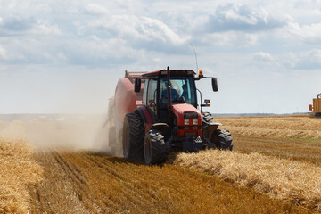 Obraz premium A round baler discharges a fresh wheat bale
