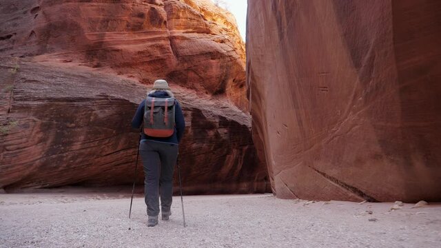 Tourist Trekking On Sandy Desert In Slot Canyon With Orange Rock Formation