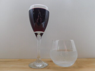 a glass of red wine and a glass of water on a wooden table.
