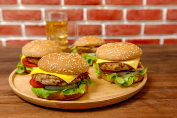 Set of pork burgers and french fries on wooden tray in front of brick wall