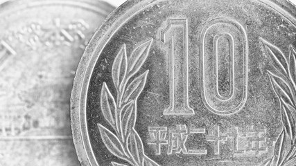 Translation: Japan 2015. Japanese coins of 10 yen on both sides close-up. Light black and white background or wallpaper. Gray backdrop about money, economy, finance, taxes and banking. Macro