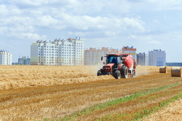 Obraz premium A round baler discharges a fresh wheat bale