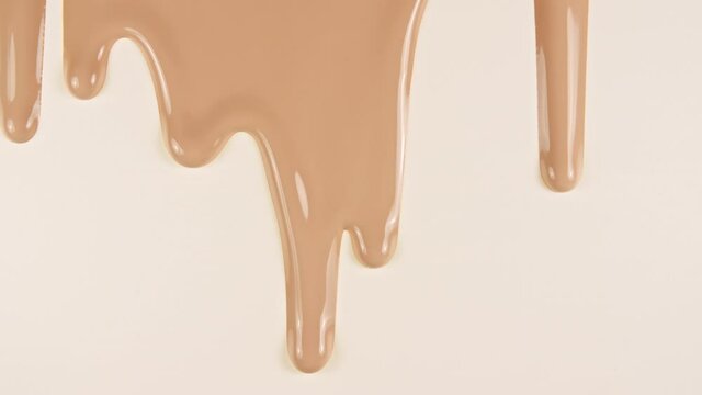 Foundation for face, smear, concealer, cosmetic liquid foundation, or cream beige color smudge flowing down on a white surface. Beauty skincare sample. Macro Shot. High quality 4k footage