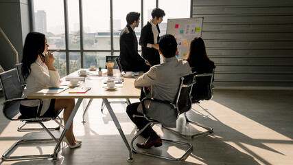 Cute and beautiful Asian businessman holding paper of chart and present information to meeting attendees. Idea for diversity team work
