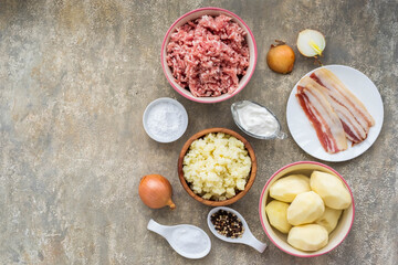 Prepared ingredients for cooking a Lithuanian dish Zeppelin from grated potatoes on a light concrete background. Lithuanian cuisine.