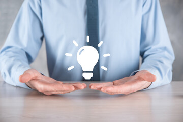 Businessman in a suit with a light bulb in his hands. Holds a glowing idea icon in his hand. With a place for text