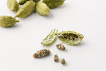 Macro photo of green whole and open cardamom pods with seeds on a white background