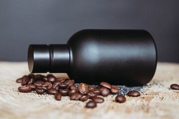 Luxury black bottle packaging lying vertically on black background on wooden table with coffee beans