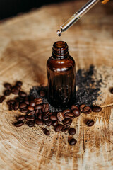 Drop falls from the pipette to  cosmetic oil bottle from top, on a wooden table with coffee beans from close up