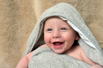 Cute happy little boy wrapped in towel after bath