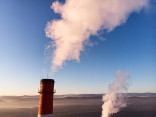 Aerial view of high smoke stack with smoke emission. Plant pipes pollute atmosphere. Industrial...