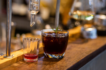 Close-up Americano is put ice in a clear glass in the distillation lab, placed on a table with a glass tube.