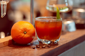 Close-up coffee with orange juice in a clear glass with ice and oranges placed on the table. Refreshing drinks in a coffee shop