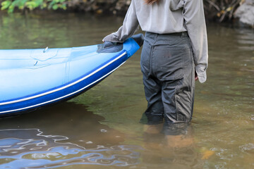 Obraz premium Close-up of a woman pulling a blue rubber boat to the shore.