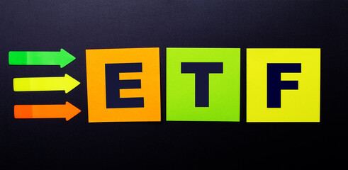 Bright multi-colored paper stickers on a black background with the text ETF Exchange Traded Funds