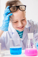 A schoolboy studies multi-colored substances in test tubes, conducts experiments - a portrait on a white background. Concept for the study of coronavirus in the laboratory