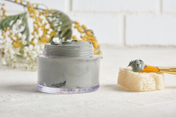 cosmetic blue clay for face and body, brush for applying face masks and mimosa on a light background