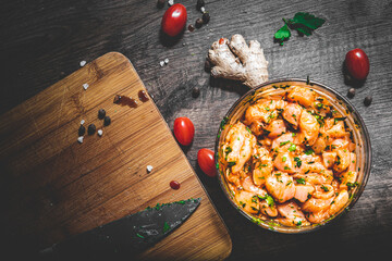 Raw marinated chicken meat with garlic, ginger and teriyaki sauce in a glass bowl on wooden table