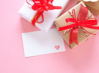 Heart-shaped punching white card and red bow tie gift box on pink background. Space for your text..