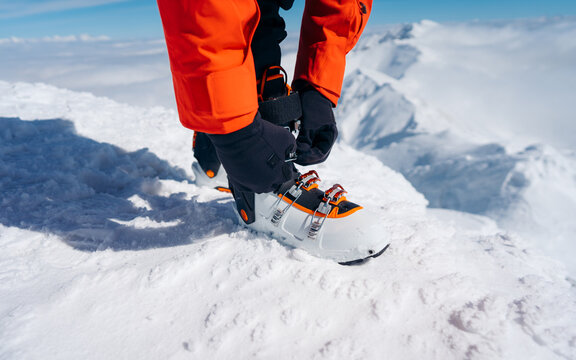 Detailed view on getting ready for skiing, fastening the boots. 
The skier wears footwear for skiing and fixes the fastener