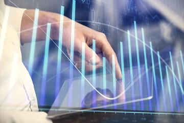 Double exposure of man's hands holding and using a digital device and forex graph drawing. Financial market concept.