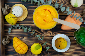 A yellow mango scrub for body care, a hand made soap and macaroons lie on a green leaf. Spa and wellness concept