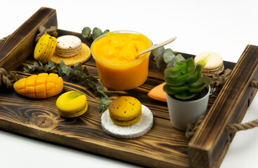 A yellow mango scrub for body care, a hand made soap and macaroons lie on a green leaf. Spa wellness