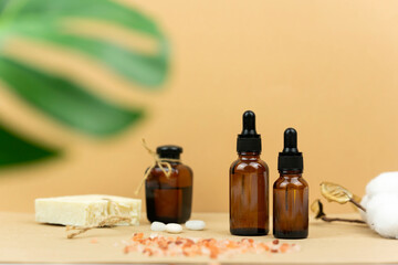 A natural oil for skin and a black hand made soap stand on a table with green monstera leaves at the background