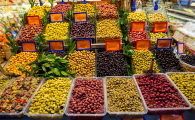 Close up of various olives standing in plastic container on deli counter in market place