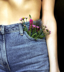 Flowers in a denim pocket on a nude girl.